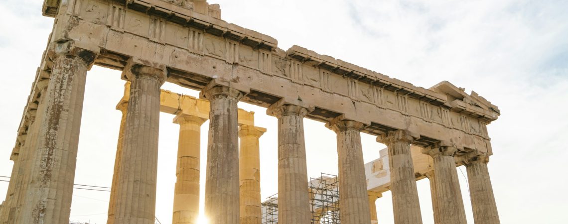 Golden hour sunlight filters through the ancient columns of the Parthenon